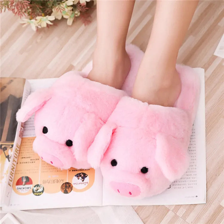 Pink pig-shaped plush floor slippers on a plain background.