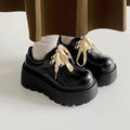 Black women's lace-up heels with a chunky rubber sole and a retro English muffin heel.