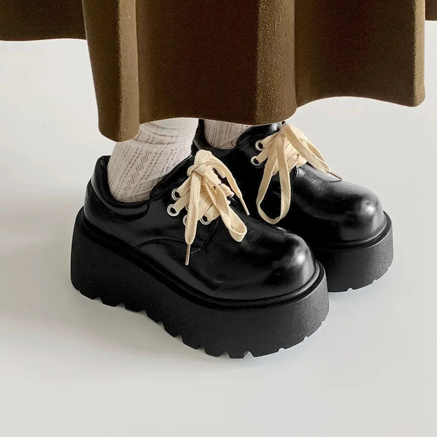Black women's lace-up heels with a chunky rubber sole and a retro English muffin heel.