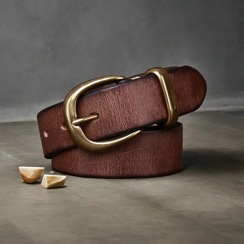 Men's black casual leather belt with copper pin buckle on a jeans background.