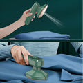 Dark green portable hand-held steam ironing machine with a ceramic panel.