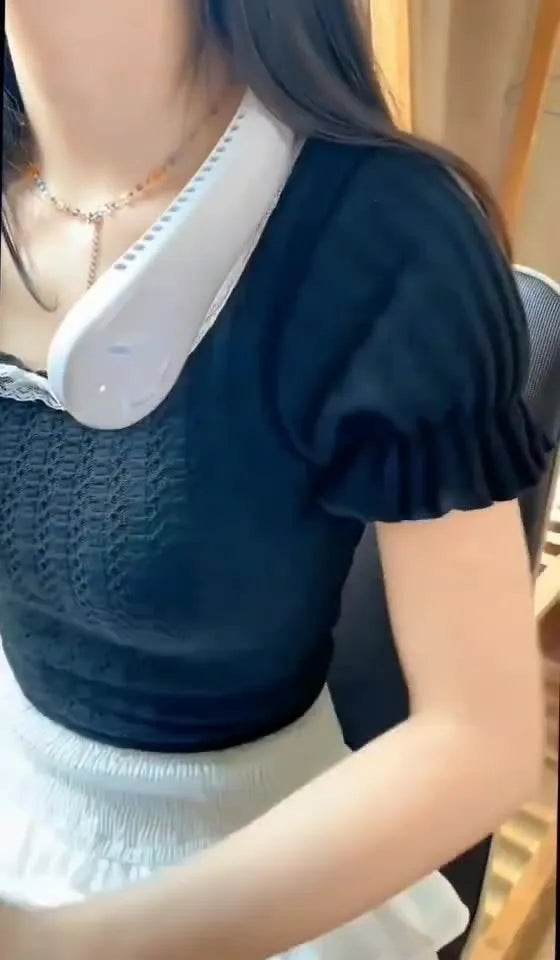White portable bladeless neck fan hanging around a person's neck showing its USB charging port.