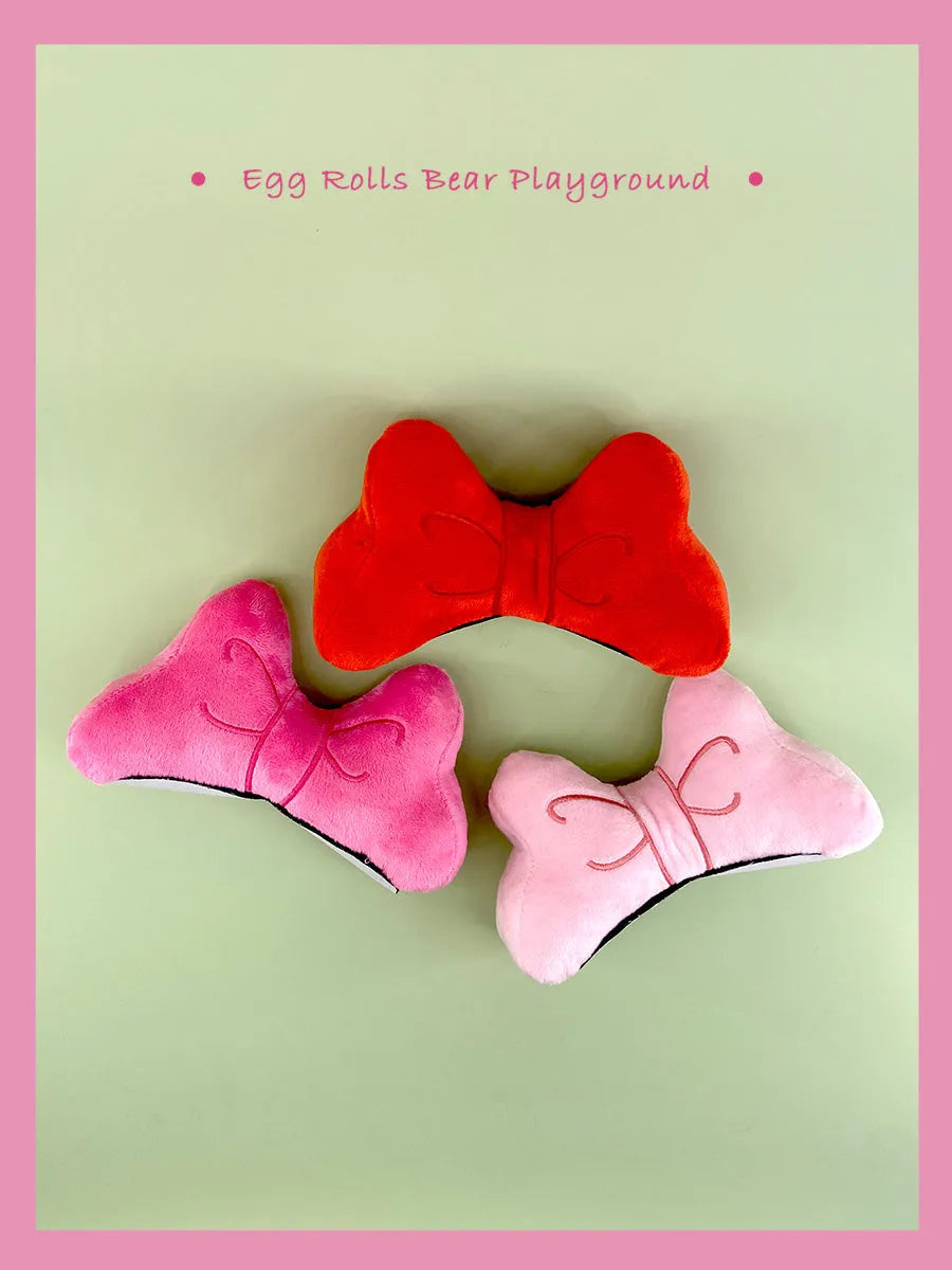 A soft plush bow decoration for helmets in red, peach pink, and rose pink colours.