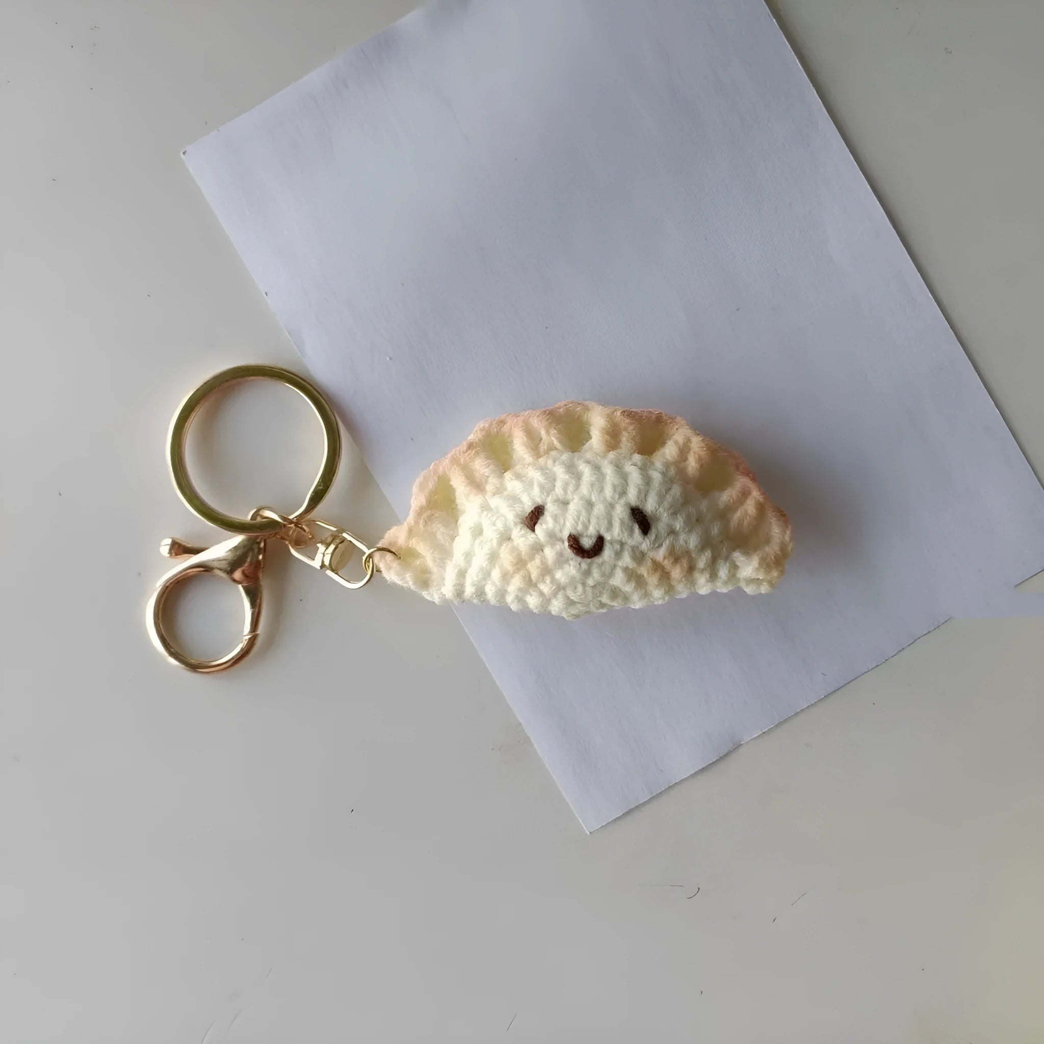 Handmade crochet dumpling pendant with keychain in plush material showing hand-stitched eye details