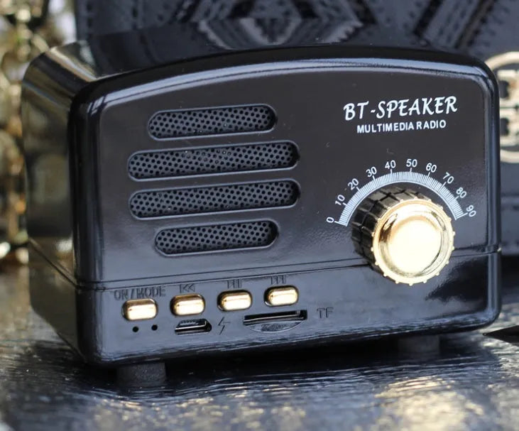 Compact Bluetooth speaker with wood grain finish, showing front grill and control buttons.