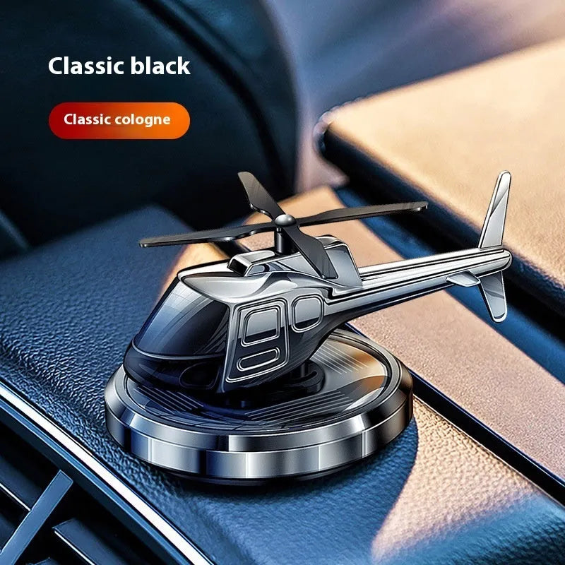Silver metal solar helicopter car air freshener ornament rotating on a dashboard.