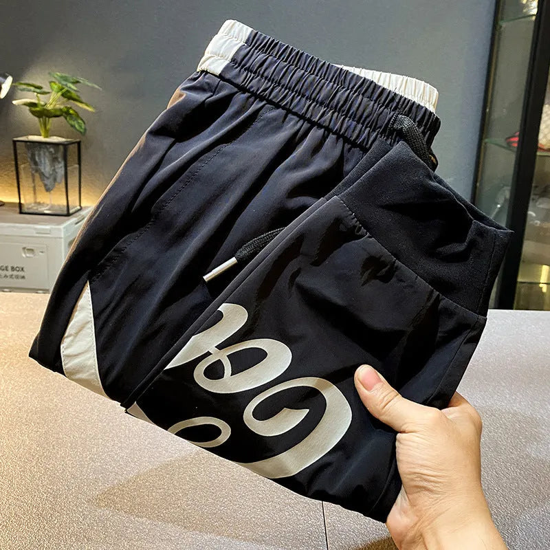 Men's solid black ultra-thin cotton cropped trousers with ankle banding on a casual model.