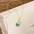 Women's pendant necklace with coloured glaze joker charm on a cotton and linen clavicle chain.