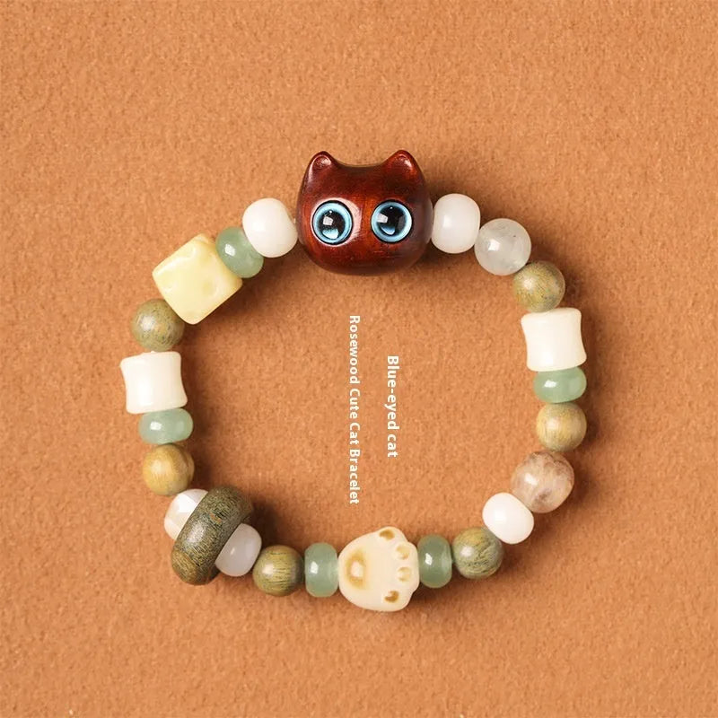 Hand-woven bracelet with jade, bodhi, and guajacwood beads, a multi-treasure cube, and a carved cat's paw charm.