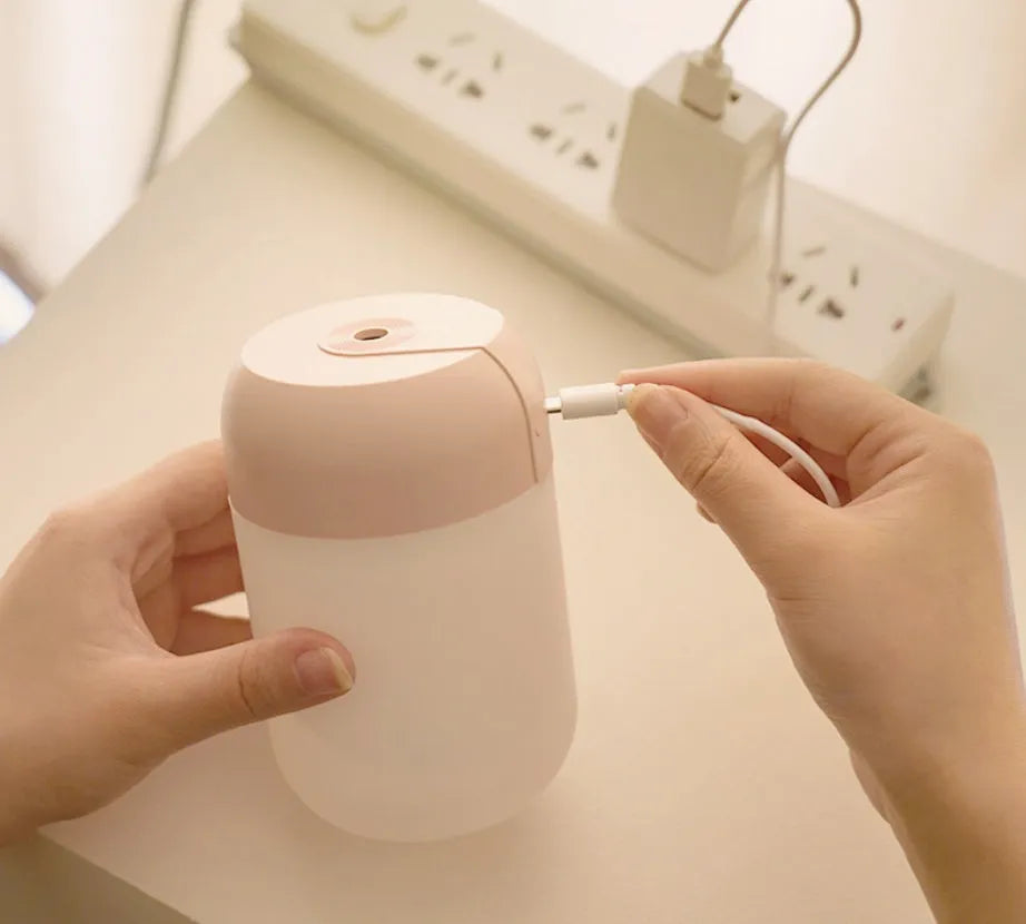 Small white cylindrical USB humidifier with charging cable for bedroom or desk use