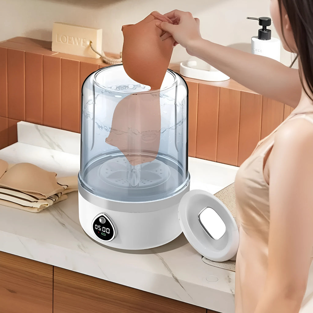 Small white portable washing machine with USB cable on a countertop.