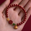 Close-up of a cinnabar Happy Eyebrow bracelet with Emperor Sandstone beads and a carved Fu character.