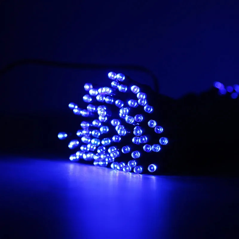 Solar outdoor LED colour light string with 22m 200 lights draped along a garden fence at dusk, showing warm white illumination and weatherproof construction