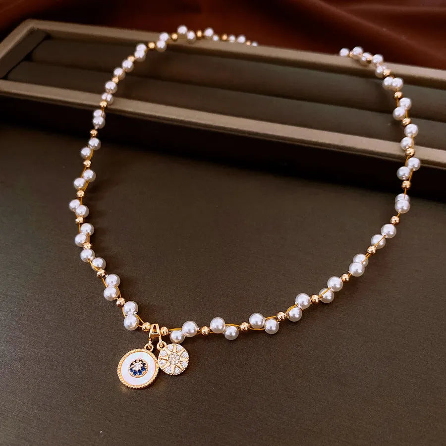 Gold electroplated necklace with round zircon-inlaid imitation pearl pendant on an adjustable clavicle chain.