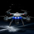 Black plastic quadrocopter drone with four propellers, a camera on front, and a remote control handle.