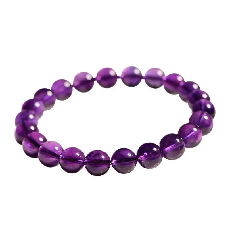 Natural polished amethyst beads scattered and strung as a bracelet on a neutral background.