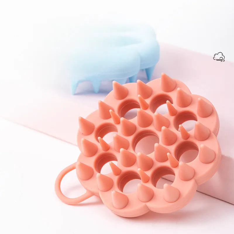 Blue silicone pet grooming brush with soft pins and ergonomic handle for wet or dry use.