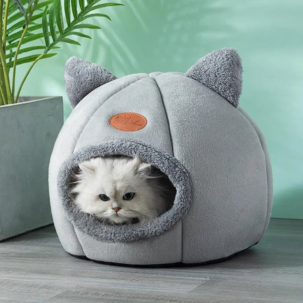 A fully enclosed cube-shaped cat sofa nest, showing the entrance hole, in a home setting.