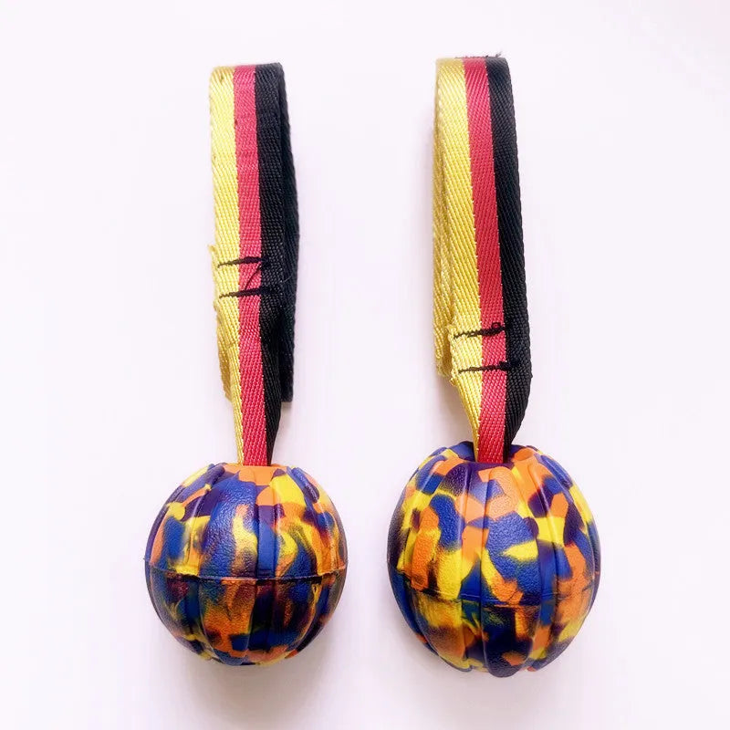 Yellow and camouflage coloured EVA floating dog balls with strings in three different sizes on a blue background.