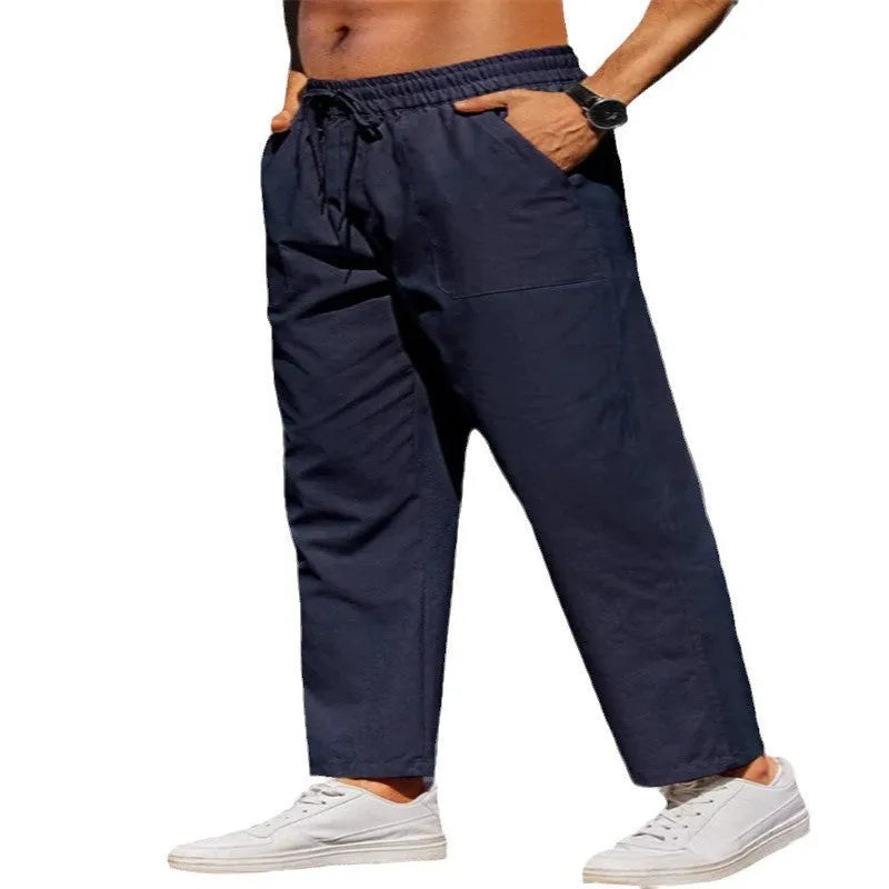 Man wearing straight-leg linen trousers in a solid colour with an elasticated waistband.