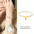Women's bracelet with Hetian jade bead and sterling silver bamboo leaf charm on a wrist.