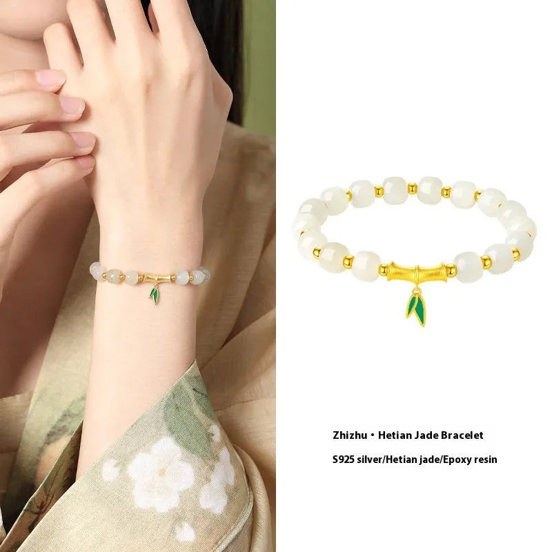 Women's bracelet with Hetian jade bead and sterling silver bamboo leaf charm on a wrist.