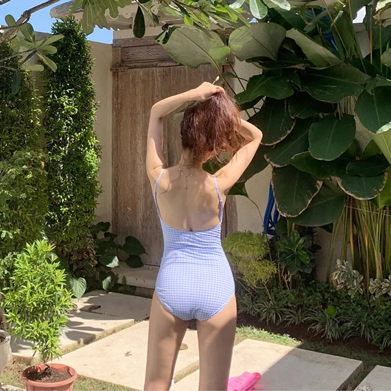Women's blue and white plaid one-piece swimsuit on a hanger