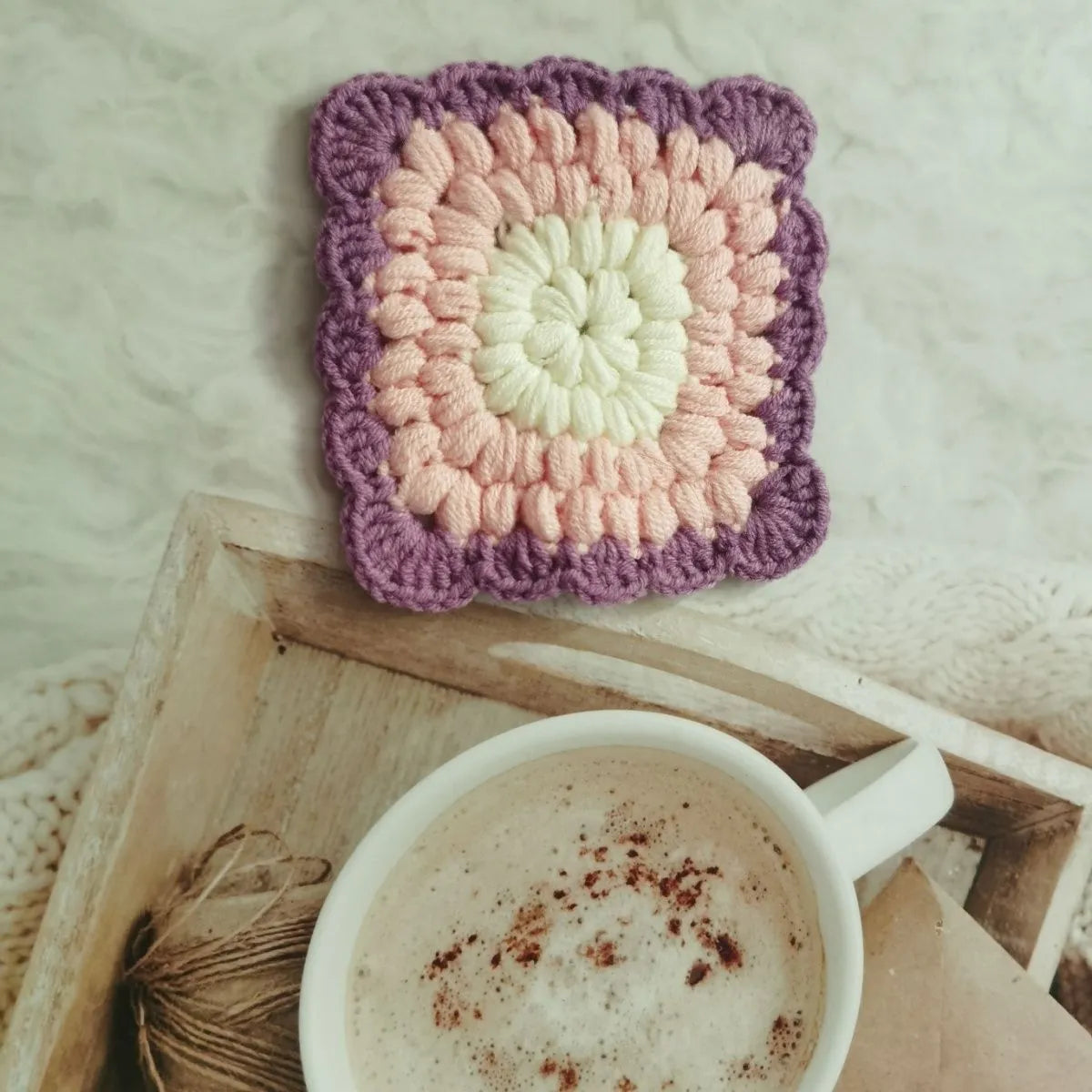 Crocheted wool cup placemat with grandmother lattice pattern in a choice of four colours.