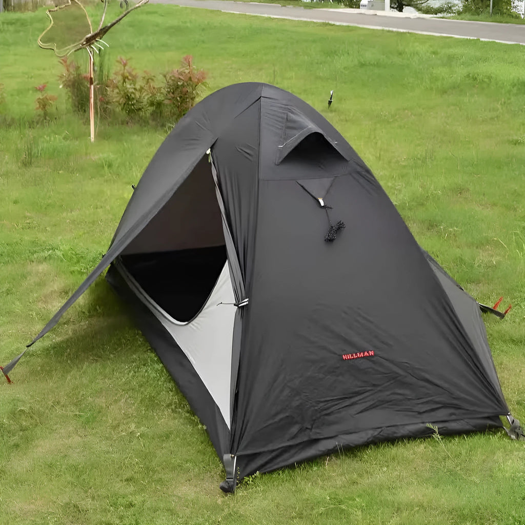 Red single person double-layer tent with aluminium poles set up outdoors.