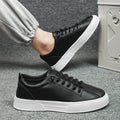 Men's black and white low top synthetic leather sports shoes with PVC sole on a plain background.