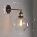 Close-up of a retro-style spherical glass wall lamp in amber, showing its aluminium holder and round shape.