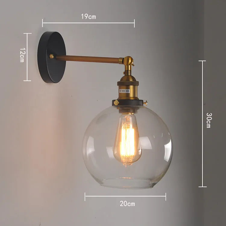 Close-up of a retro-style spherical glass wall lamp in amber, showing its aluminium holder and round shape.