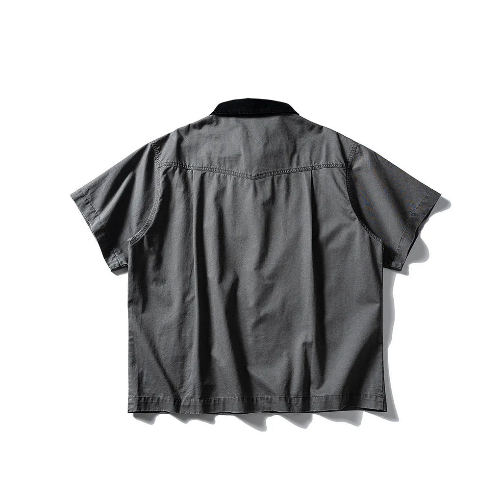 A khaki coloured, loose-fitting short sleeve cotton overalls shirt with a cardigan style on a hanger.