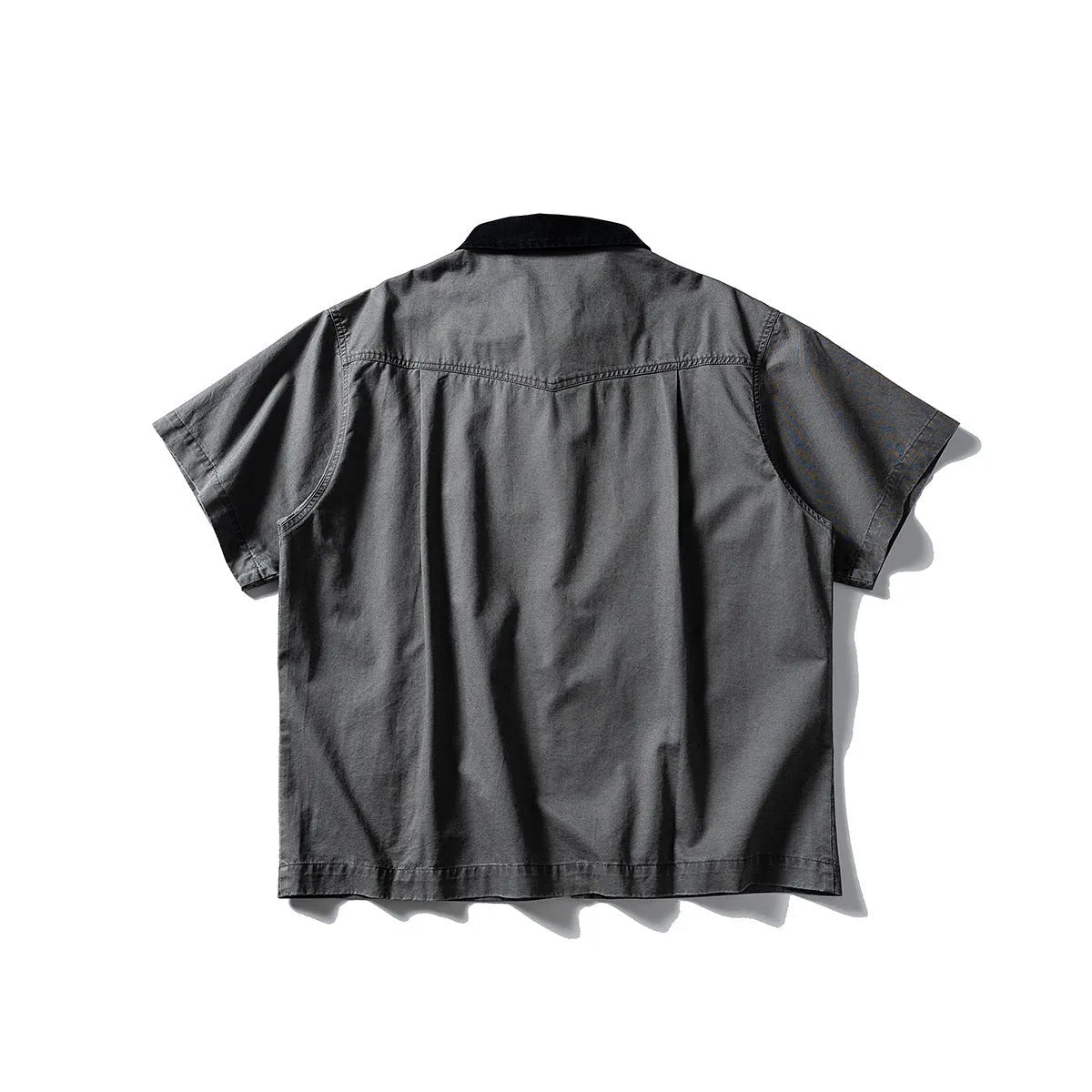A khaki coloured, loose-fitting short sleeve cotton overalls shirt with a cardigan style on a hanger.