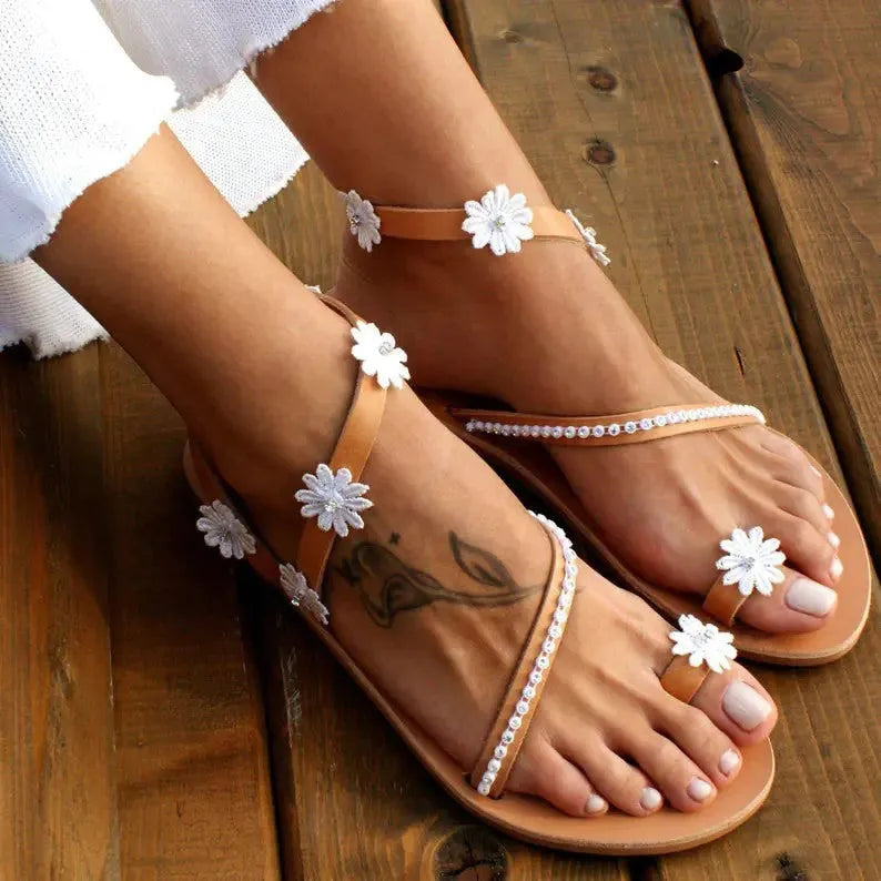 Brown women's Roman sandals with floral pattern and flat rubber sole.