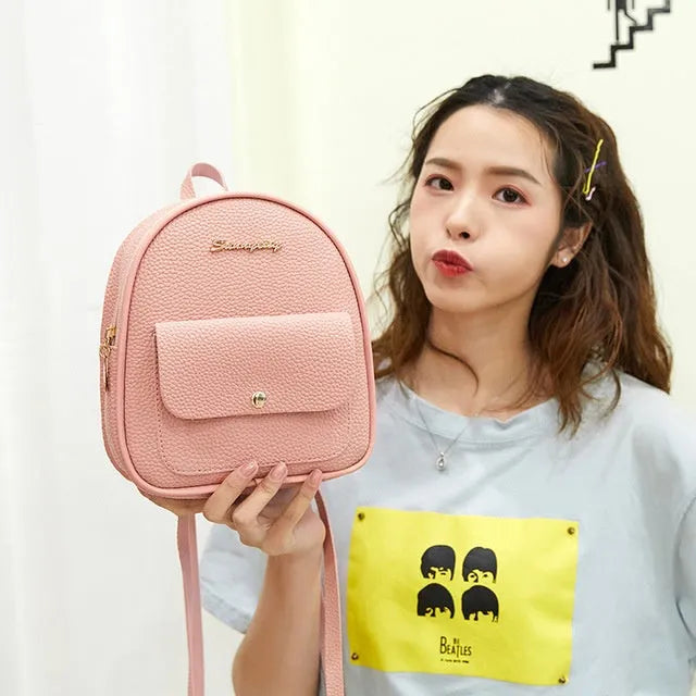 Small black PU women's backpack with zip, shown alongside a mobile phone for scale