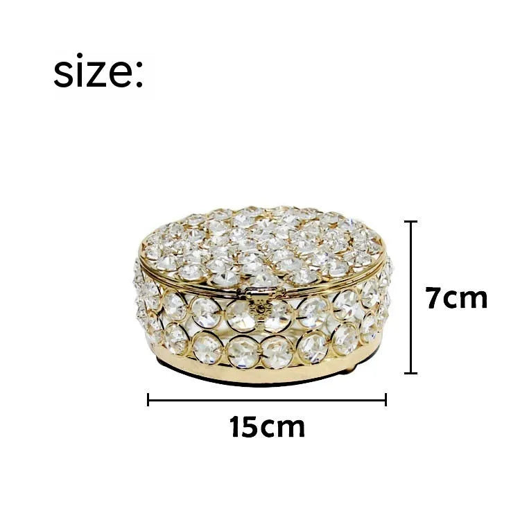 French gold metal jewelry box with a clear crystal glass lid and a lock, shown on a surface.