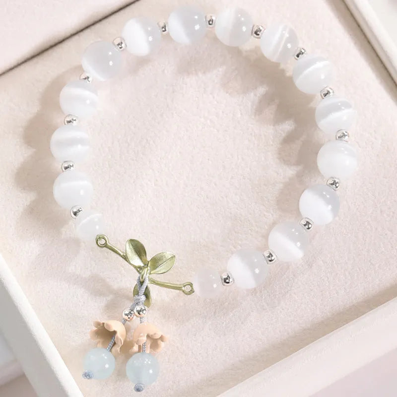 Women's opal cat's eye stone bracelet with diamond-shaped beads on wrist.