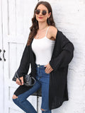 A women's loose-fitting solid colour acrylic sweater coat on a hanger.