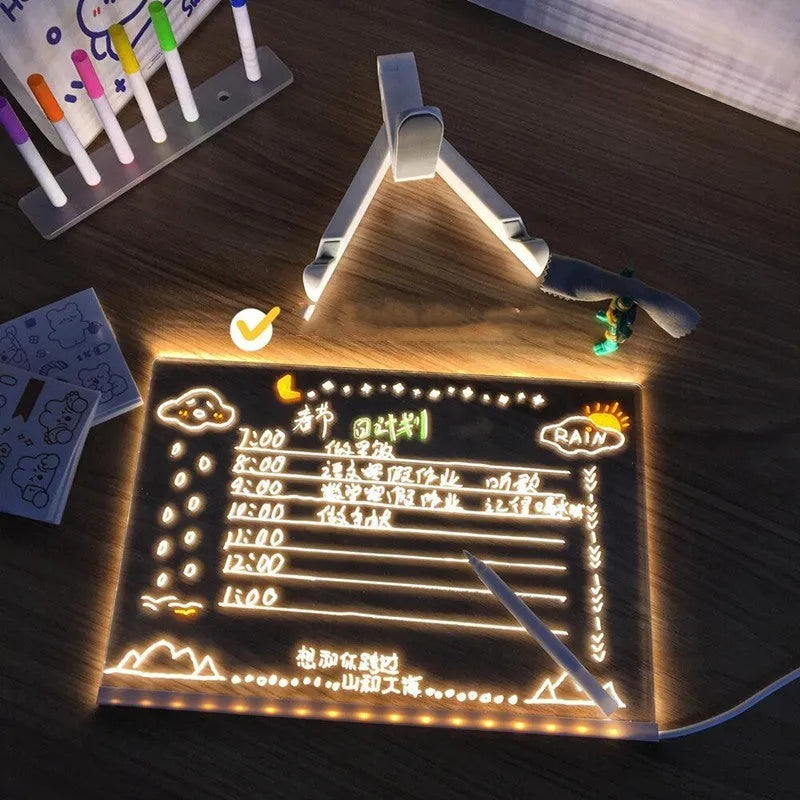 Acrylic DIY LED message board night light on a desk, showing writing on the glowing transparent surface with pens nearby.