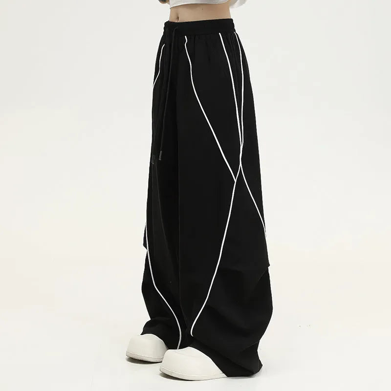Black striped wide-leg pleated sports trousers showing loose fit and mid-waist design