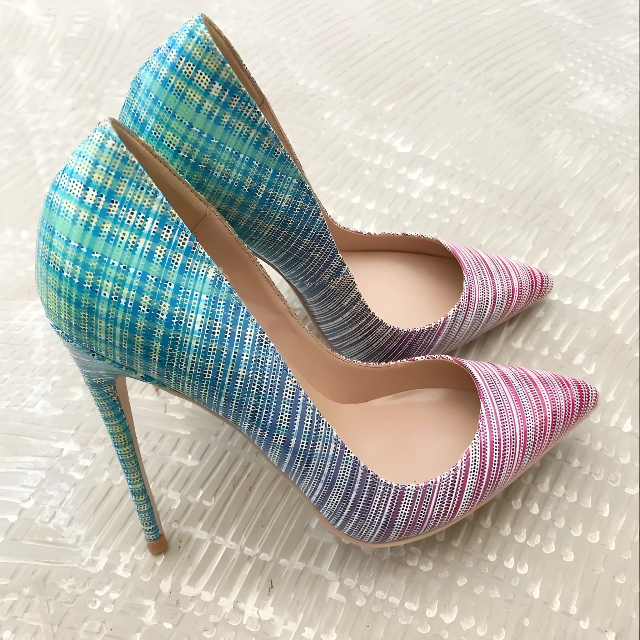 A pair of women's pink and blue gradient patent leather high heel shoes with a pointed toe.