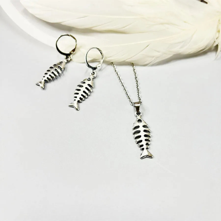 Close-up of silver fishbone pendant earrings on a white background, showing O-shaped chain detail.