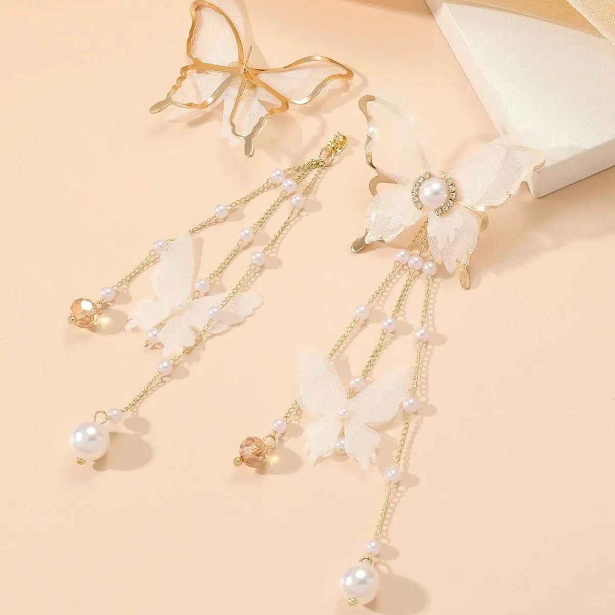 A pair of white butterfly-shaped earrings with tassel lace and pearl rhinestone details on electroplated copper alloy.