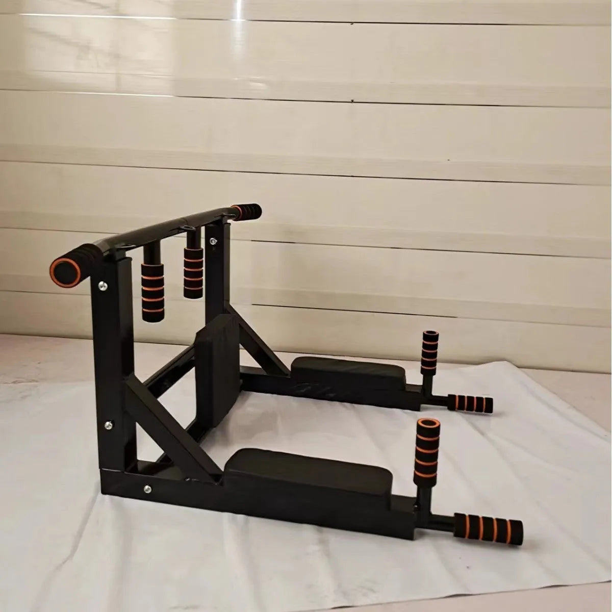 Black steel wall-mounted fitness rack with sandbag hanger, parallel bars, and pull-up bar.