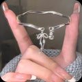 Silver bow coloured adjustable zinc alloy bracelet with an opening bow bell design.
