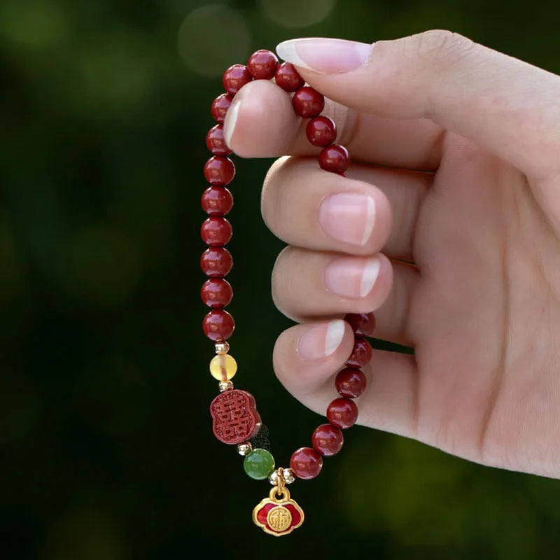 Close-up of a cinnabar Happy Eyebrow bracelet with Emperor Sandstone beads and a carved Fu character.