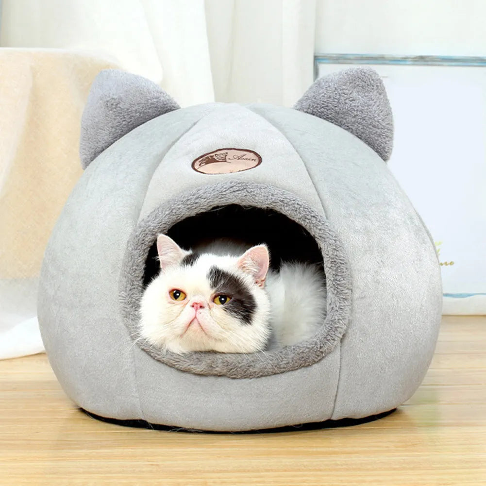 A fully enclosed cube-shaped cat sofa nest, showing the entrance hole, in a home setting.