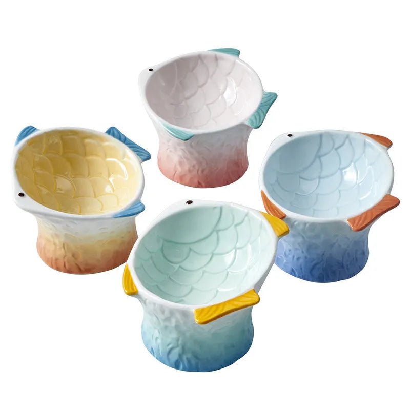 Blue fish-shaped ceramic cat bowl with tilted angle on a wooden surface