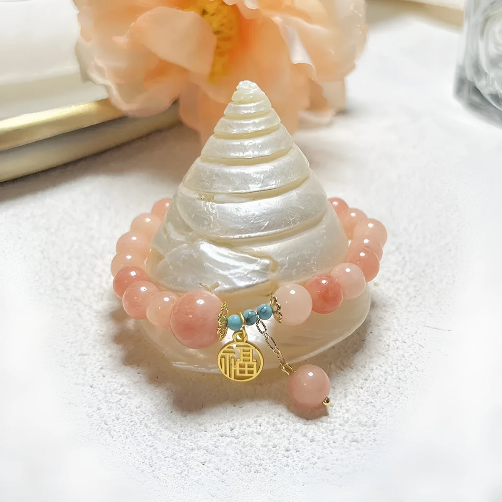 A simple pink natural stone and alloy bracelet with an adjustable clasp on a wrist.